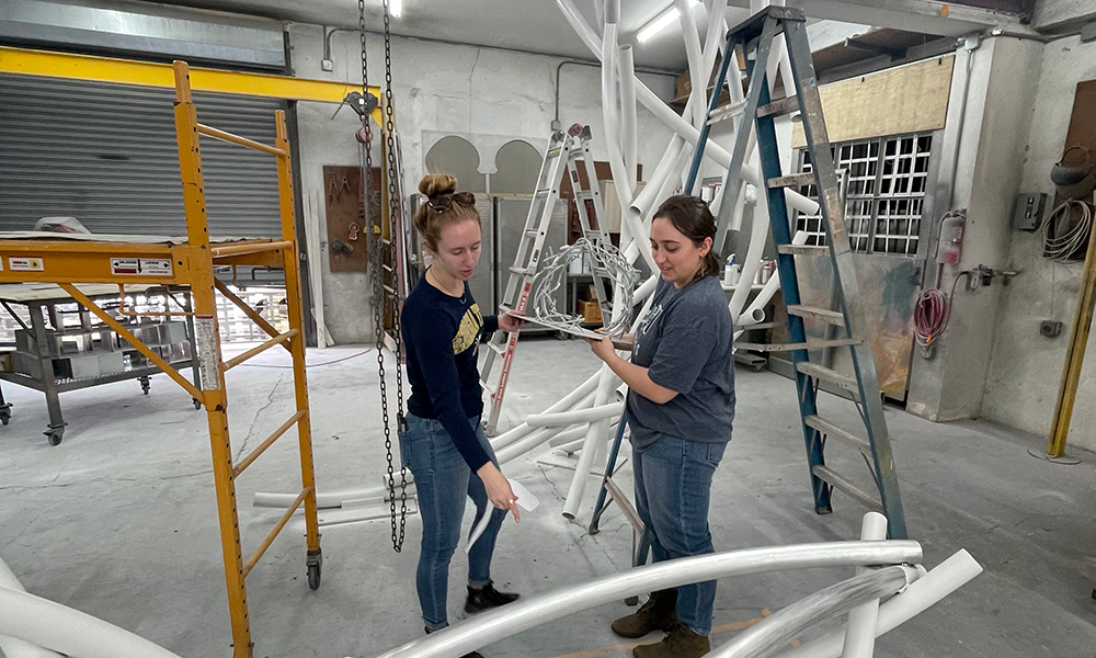 Elizabeth Kelly and Danielle Sisson holding a model of the sculpture.