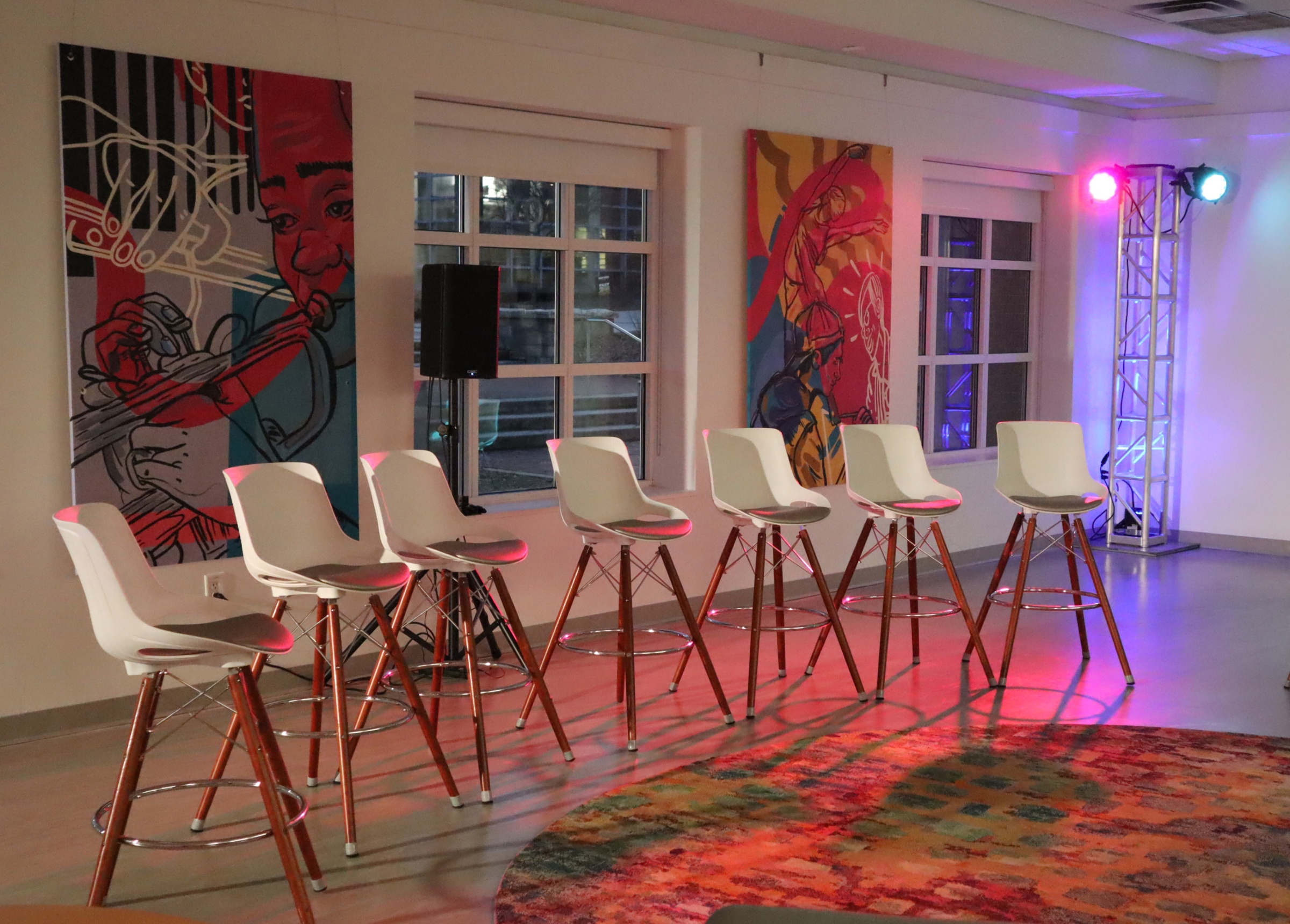 Tall chairs set up for panel discussion with purple and blue lighting in lobby of Ferst Center