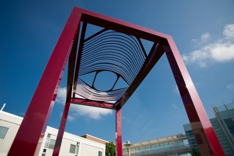 Open rectangular frame, painted red, with an open pattern of curved bars on the top resembling an eye looking down