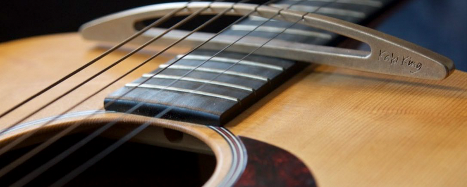 Detail of the soundhole and metal bridge with Kaki King engraved of an acoustic guitar. / Photo by Kaki King