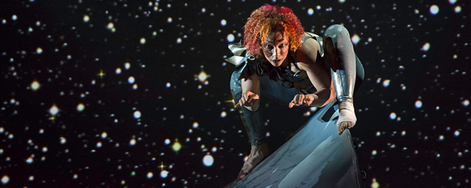Andromeda perches out of her wheelchair on the sharp peak of the ramp. From atop of this mountain, she looks directly into our eyes. Her hair is flame red; a constellation of stars sparkles behind her. Photo: BRITT/Jay Newman 