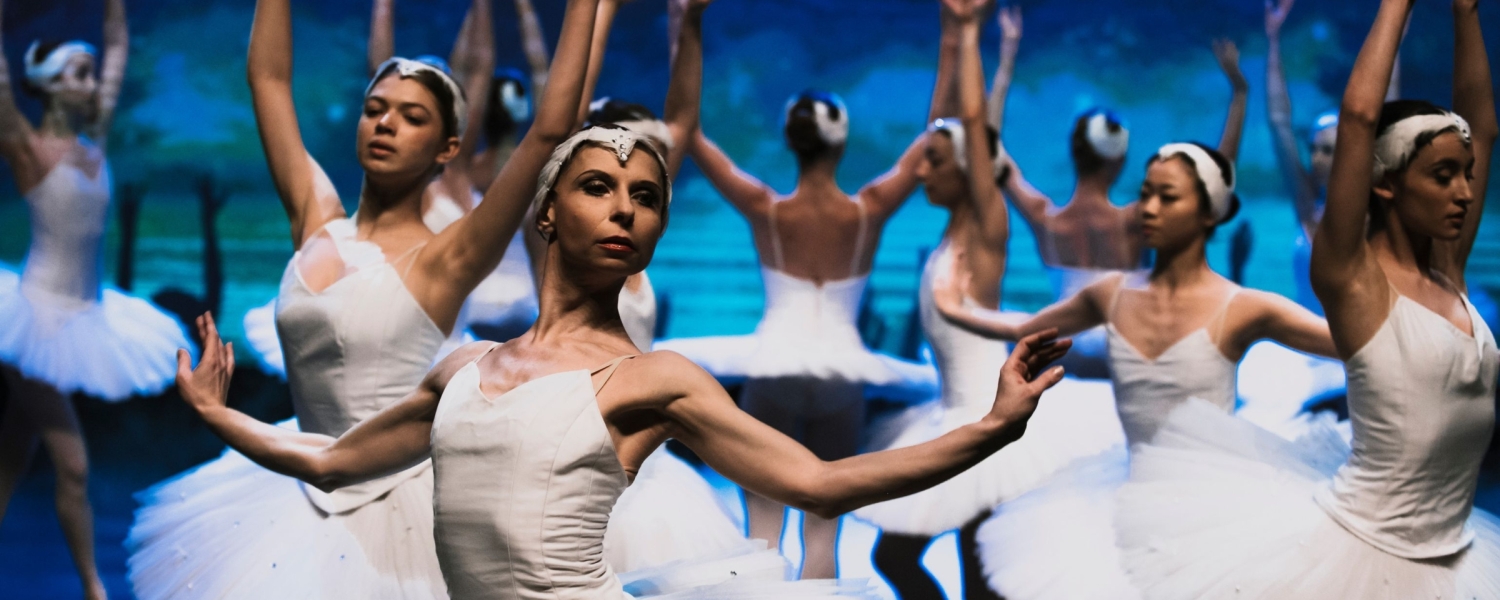 Ballet dancers wearing white with blue background