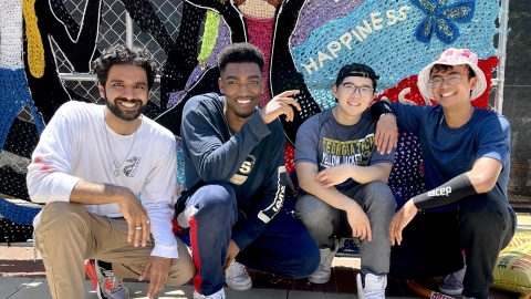 Four young men from the Tech student organization TekStyles, crouch in front of the mural.