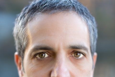 A man with close cropped grey hair stares directly at the camera.