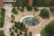 Aerial view of the 80 foot tall stainless steel spire based in a pool of water with fountain spray