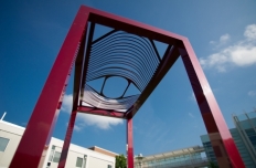 Open rectangular frame, painted red, with an open pattern of curved bars on the top resembling an eye looking down