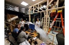 A group of people in a workshop busy with with tools and computers