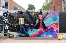 A crocheted mural hung on a chain link fence. Yarnbombing by London Kaye.