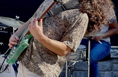 A young man plays electric guitar, his head thrown back and his long hair loose. GT Music Network jazz musicians.