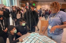 A woman explains the projection in front of her to a handful of eager students.