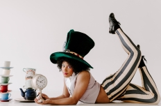 dancer wearing green top hat, white sleeveless shirt, and stripe pants